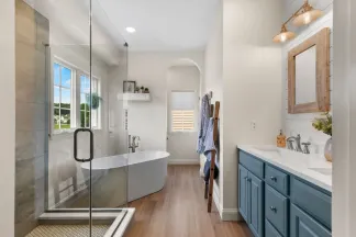 Bathroom remodel in Landisville, PA with a freestanding soaking tub, glass shower, and blue vanity with brass fixtures.