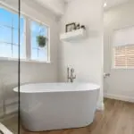 Freestanding soaking tub in a Landisville, PA bathroom remodel with a matte black floor-mount faucet and window nook.