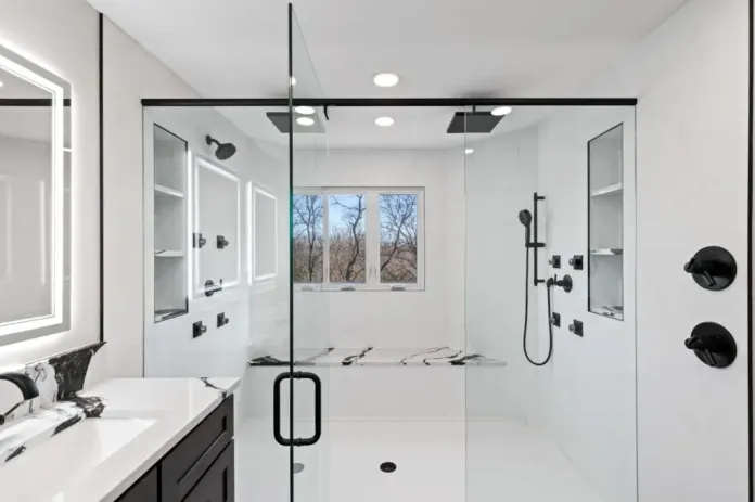 Marble-tiled walk-in shower with dual black rainfall showerheads, built-in bench, and black-framed glass door.
