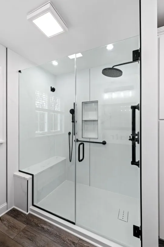 lititz, PAAlt text: Walk-in shower remodel in Lititz, PA with a black-framed sliding glass door, black base, and matte black fixtures. Caption: This Lititz, PA shower remodel features a sleek black-framed sliding glass enclosure paired with a matching black shower base and matte black hardware, including a handheld sprayer and built-in shelving. Light wood-look flooring and white wall tile keep the space bright while the black accents add contrast. Next photo whenever you're ready.downtown lancaster, PAThought processThought processAlt text: Bathroom remodel in downtown Lancaster, PA with black-framed mirrors reflecting a marble-tiled shower with sliding glass doors. Caption: This downtown Lancaster, PA bathroom remodel features sleek black-framed mirrors above a white quartz vanity, with polished chrome faucets and a glass-enclosed shower with marble-look tile reflected behind. A pendant light adds a clean, modern touch overhead. Next one whenever you're ready.Thought processThought processAlt text: Marble-tiled walk-in shower with dual black rainfall showerheads, built-in bench, and black-framed glass door. Caption: This spa-style walk-in shower features floor-to-ceiling marble-look tile, dual black rainfall showerheads, a built-in bench with a book-matched marble slab, and recessed niche shelving. Matte black hardware and a black-framed glass door contrast beautifully against the white marble, while a window brings in natural light and a wooded view. Next one whenever you're ready — and let me know if you want a location added to this one.Thought processThought processAlt text: Bathroom remodel with dark wood double vanity, white countertop, black-framed mirrors, and a tiled glass shower. Caption: This bathroom remodel pairs a dark wood double vanity with a white quartz countertop and black-framed mirrors, set against warm terracotta walls. Brass and nickel wall sconces add a mixed-metal touch, while the glass-enclosed shower features square tile walls, a built-in bench, and a window for natural light. Next one whenever you're ready.Alt text: Frameless glass shower with black hardware, built-in bench, and round black rainfall showerhead over marble-look tile.