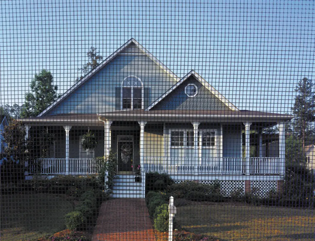 A two-story blue-grey craftsman style house with a large wraparound front porch, white railings, and a brick walkway.